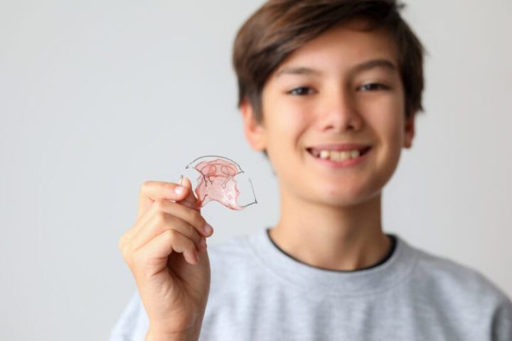 Dental braces. Teenager boy smiling holding orthodontic appliance dental treatment to improving bite gap.